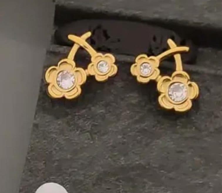 Gold flower stud earrings on slate